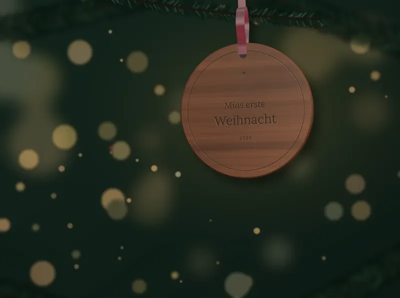 Ein gravierter Weihnachtsschmuck aus Nussbaumholz mit der Aufschrift «Mias erste Weihnacht» hängt an einem Tannenzweig.